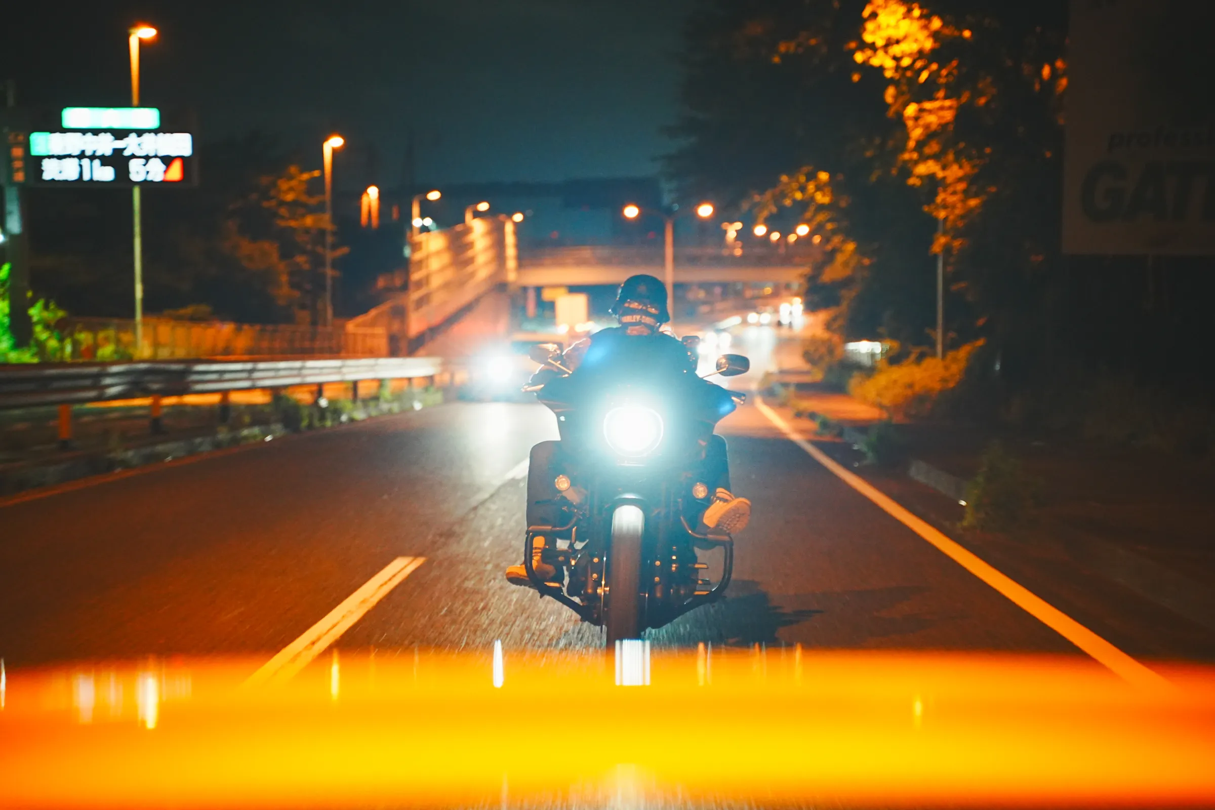 夜の幹線道路でバイクを追走する——手前にダニーのボンネット